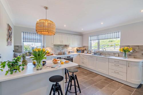 a kitchen with white cabinets and a large island with stools at Ty Eithin in Gwbert