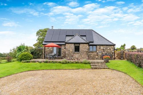 a stone house with a black roof at Little Hill End Stables - Reynoldston in Reynoldston