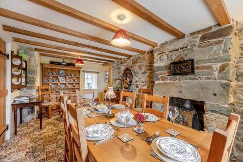a dining room with a table and a stone fireplace at Bron LLety Ifan in Arthog
