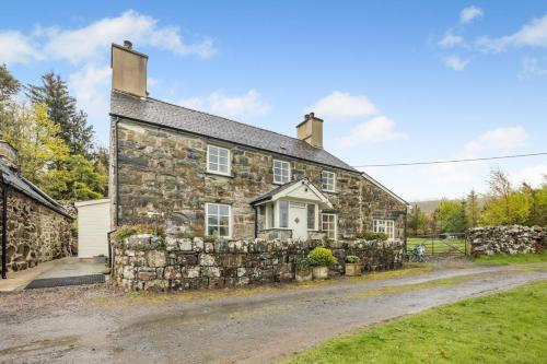 an old stone house with a stone wall at Bron LLety Ifan in Arthog