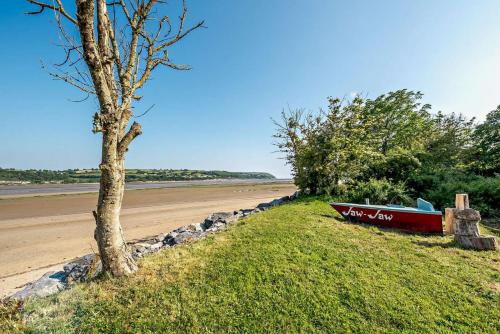 a red boat sitting on the grass next to a beach at Eryl in Ferryside