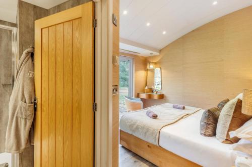 a bedroom with a bed and a door to a room at Pinelands at Bryn Tanat in Llanymynech
