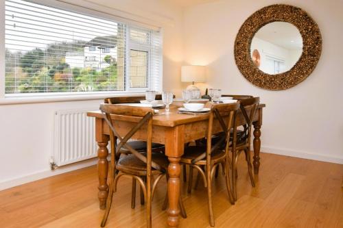 a dining room table with chairs and a mirror at Nyth yr Wylan in Aberdyfi