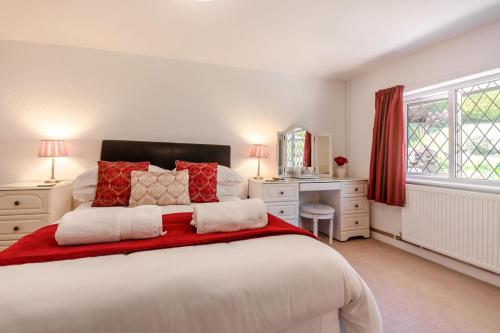 a bedroom with a large white bed with red pillows at Bryn Tirion Cottage in Llanfair Talhaiarn