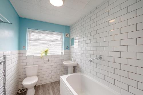 a white bathroom with a tub and a toilet at Cludfan Abersoch in Abersoch