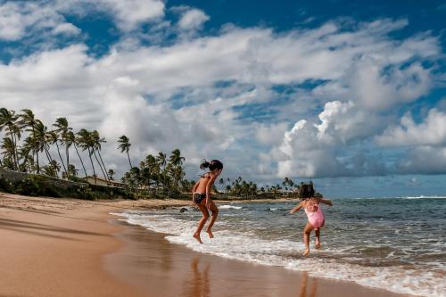 two girls playing in the water on the beach at Pousada a Capela in Arembepe