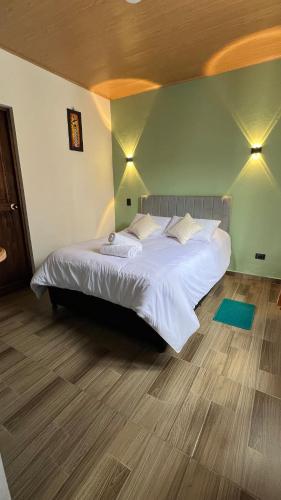 1 dormitorio con 1 cama blanca grande y suelo de madera en La Caracola, en Villa de Leyva