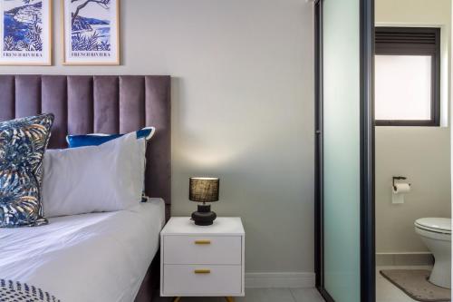 a bed with a purple headboard and a lamp on a night stand at AlimamaSpaces Phillys Whisken in Midrand