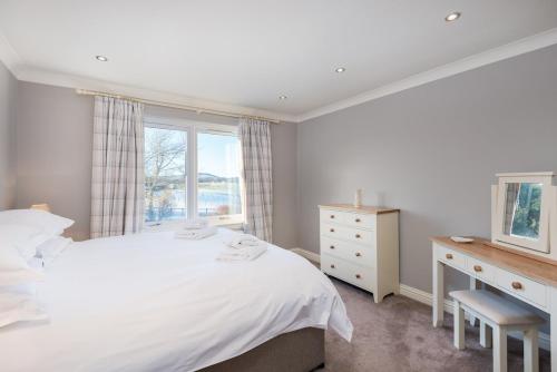 ein weißes Schlafzimmer mit einem Bett und einem Fenster in der Unterkunft Balass Lodge near The Old Course St Andrews in Fife
