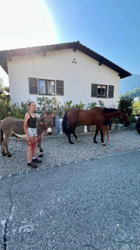 a woman standing in front of two horses and a house at Casa Flora in Gordola