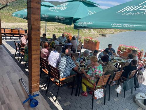 a group of people sitting at tables under an umbrella at Lagos Lac de Pescuit in Boiştea-Boerească