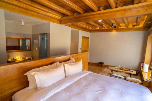 a bedroom with a white bed and wooden ceilings at Bamei Sonam Farm in Qianning