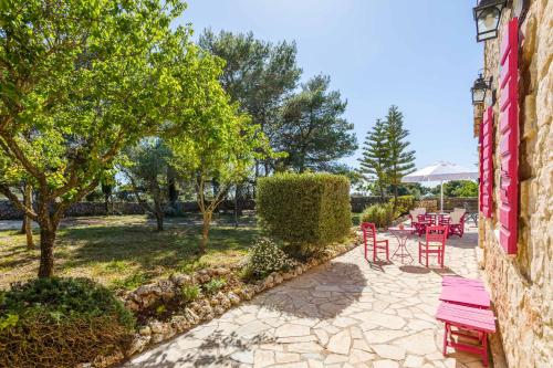 a patio with red chairs and tables in a park at Villa Ariadne Aresti in Agios Leon