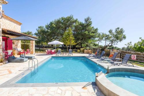 a swimming pool in a yard with chairs and umbrellas at Villa Ariadne Aresti in Agios Leon