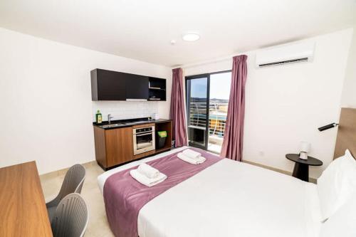 a hotel room with a bed and a tv and a window at Bright & Cozy Studio in St Paul's Bay