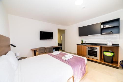a hotel room with a bed and a flat screen tv at Bright & Cozy Studio in St Paul's Bay