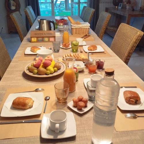 un lungo tavolo con cibo per la colazione e una bottiglia d'acqua di Les Hauts de Cabanoule Générargues a Générargues