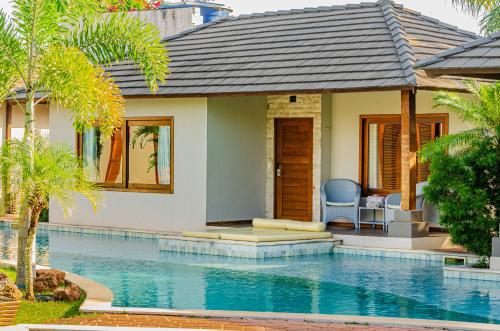 a villa with a swimming pool next to a house at AWARA POUSADA BOUTIQUE in São Miguel do Gostoso
