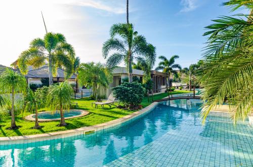 a swimming pool with palm trees in a resort at AWARA POUSADA BOUTIQUE in São Miguel do Gostoso