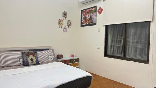 a white bedroom with a bed and a window at Jiajia Inn in Lugang