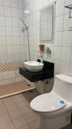 a bathroom with a sink and a toilet and a mirror at Jiajia Inn in Lugang