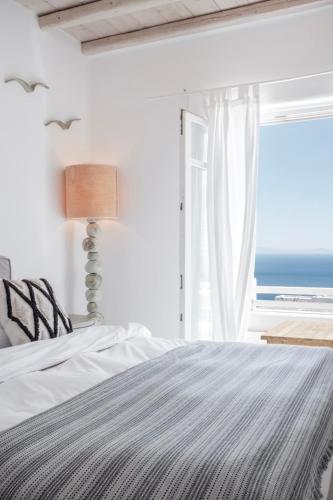 a bedroom with a bed and a window with the ocean at Mando Pool Villas w Sea Views - Five Bedrooms in Super Paradise Beach