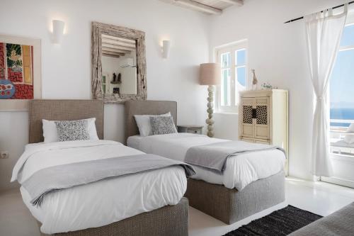 a white bedroom with two beds and a mirror at Mando Pool Villas w Sea Views - Five Bedrooms in Super Paradise Beach