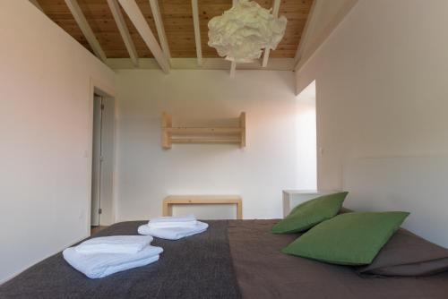 1 dormitorio con 1 cama grande con almohadas verdes en Casa do Sanguinho - Estúdio, Quinta do Rochão, en Terra Alta