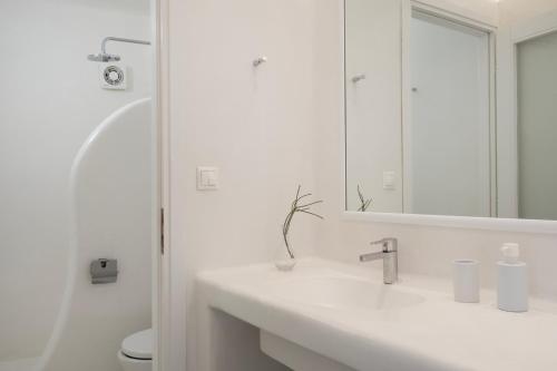 a white bathroom with a sink and a mirror at Mando Pool Villas w Sea Views - Five Bedrooms in Super Paradise Beach