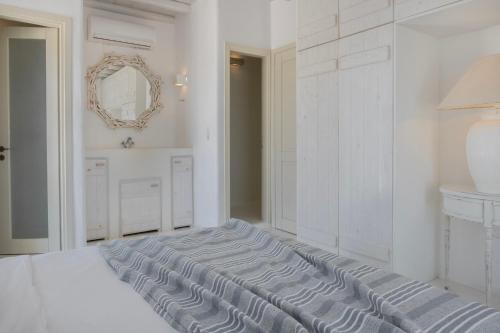 a white bedroom with a bed and a mirror at Mando Pool Villas w Sea Views - Five Bedrooms in Super Paradise Beach