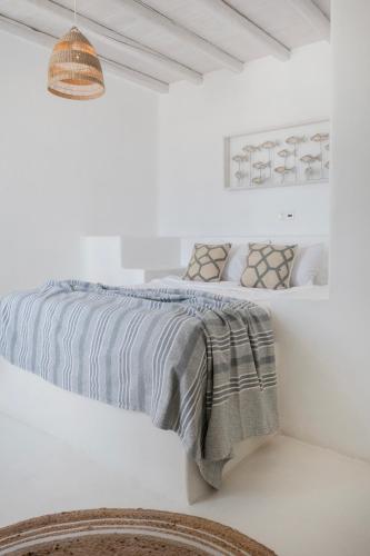 a white bedroom with a bed with a gray blanket at Mando Pool Villas w Sea Views - Five Bedrooms in Super Paradise Beach