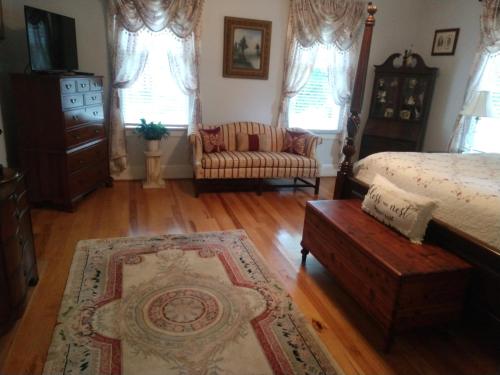 a bedroom with a bed and a couch and a chair at Virginia Cliffe Inn in Glen Allen