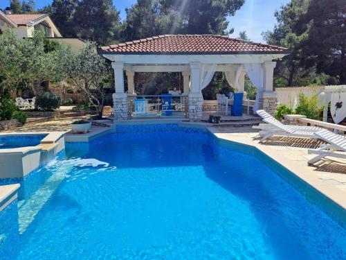 a pool with a gazebo and blue water at Villa Stone House Poplat in Vela Luka