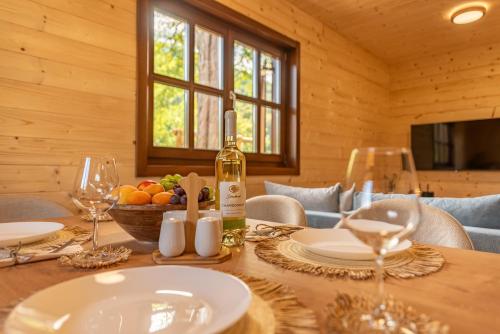 a dining room with a table with a bottle of wine at Forest Paradise in Ličko Petrovo Selo