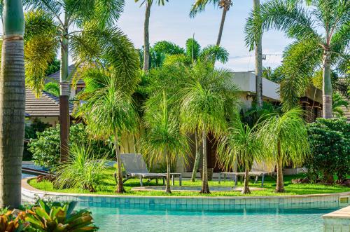 a bench next to a swimming pool with palm trees at AWARA POUSADA BOUTIQUE in São Miguel do Gostoso