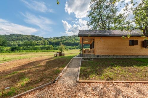 a building with a dirt road next to a field at Forest Paradise in Ličko Petrovo Selo