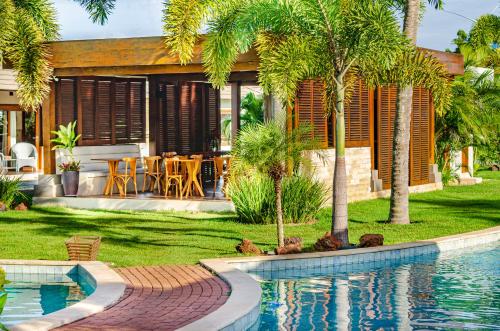 a house with a swimming pool and palm trees at AWARA POUSADA BOUTIQUE in São Miguel do Gostoso