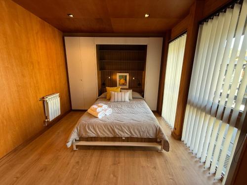 une chambre avec un lit dans une pièce avec des fenêtres dans l'établissement Departamento 3 ambientes, modernoso, cálido y a media cuadra de la calle principal. 2 PAX (V420), à San Martín de los Andes