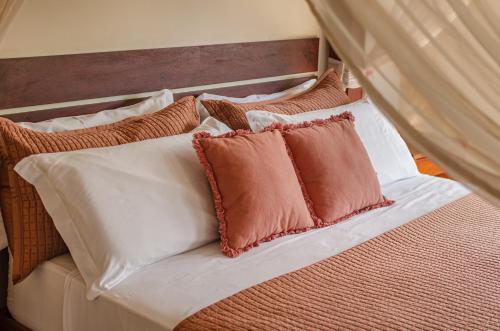 a bed with brown and white pillows on it at AWARA POUSADA BOUTIQUE in São Miguel do Gostoso
