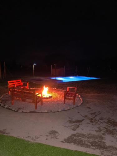 two benches sitting around a fire pit at night at Cabaña en Parcela, Valle del Elqui in Diaguita