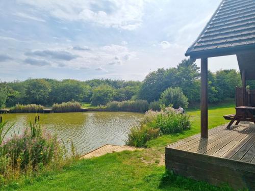 a wooden deck with a gazebo next to a lake at Willow Plus 6 Hot Tub in Garton