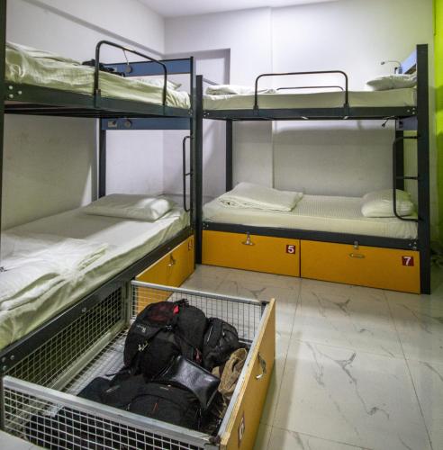 a room with three bunk beds and a basket of luggage at Backpackers Villa Mumbai in Mumbai