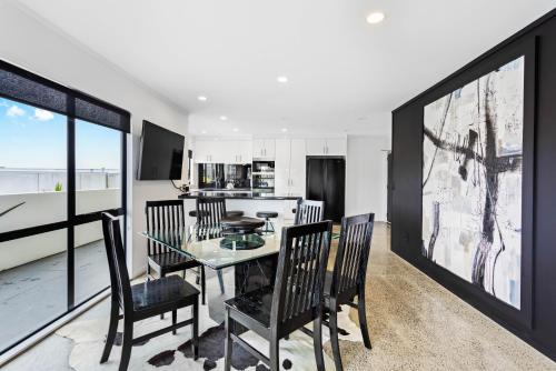 a dining room with a glass table and chairs at Awesome Designer 3BR Apt in the Heart of Manukau in Auckland