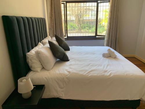 a bedroom with a white bed with pillows and a window at Palm Haven on Sarnia in Durban