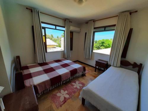 Un dormitorio con una cama y dos ventanas en Casa Lyrio - Itacimirim, en Camassari