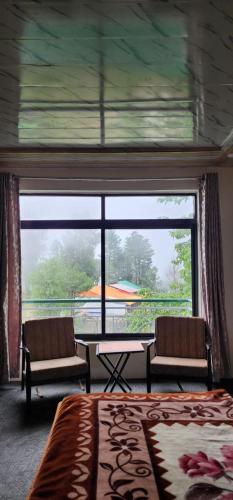 a bedroom with a large window and a table and chairs at Mezbaan guest house in Nathia Gali
