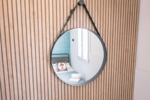 a round mirror hanging on a wall in a bathroom at Mennuli e mari - sicily home in Brucoli