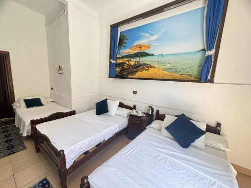 2 posti letto in una camera con una foto della spiaggia di Acropole Alexandria Hotel ad Alessandria d'Egitto