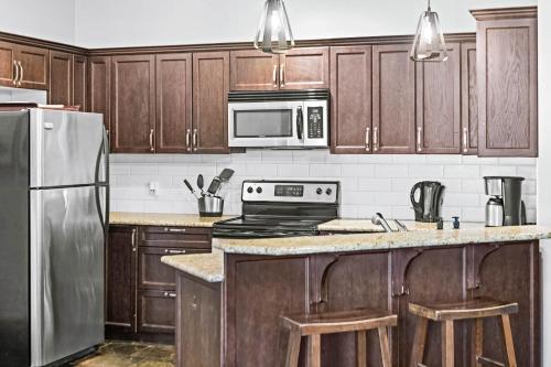 a kitchen with wooden cabinets and stainless steel appliances at Mountain Getaway in Canmore - Sleeps 6 - Pool & Hottub in Canmore
