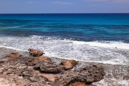a beach with rocks in the water and the ocean at The Mint Resort Isla Mujeres in Isla Mujeres